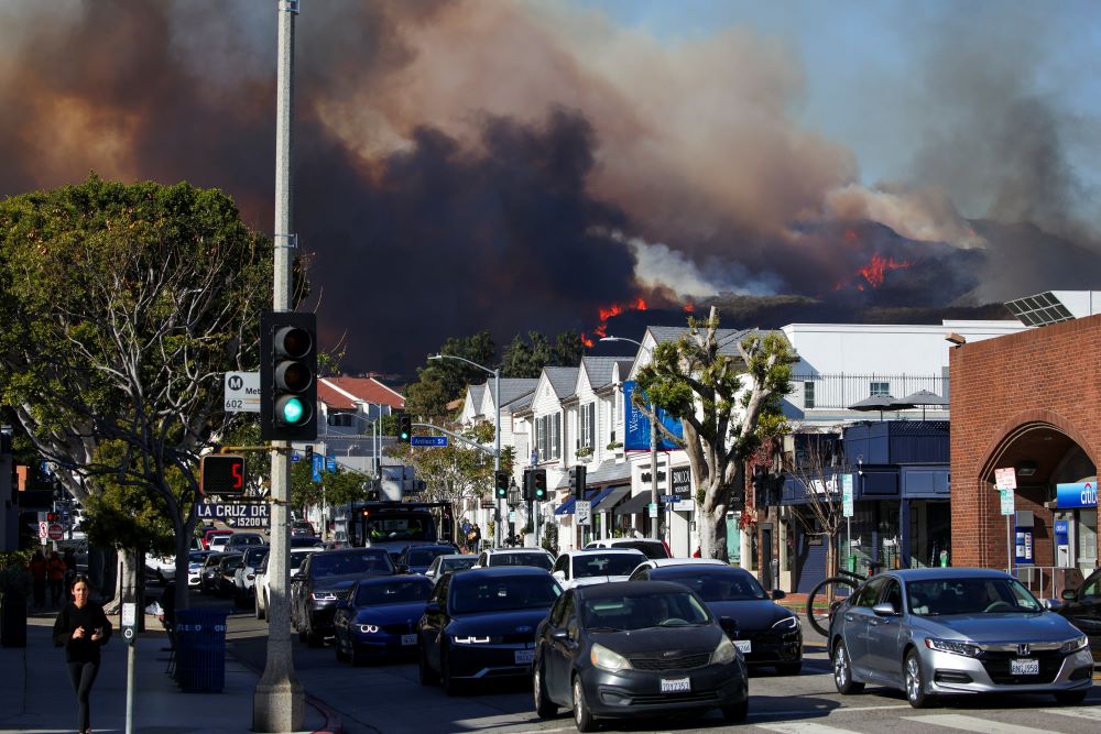 People evacuate as smoke rises from a wildfire burning near Pacific Palisades on the west side of Los Angeles during a weather-driven windstorm in Los Angeles Jan. 7, 2025. (OSV News/Reuters/Daniel Cole)