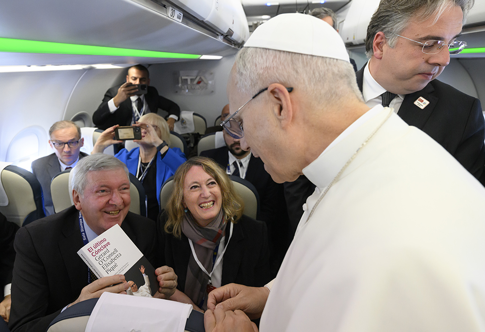 Elisabetta Piqué and Gerard O'Connell give a Spanish-language edition of their book, The Election of Pope Leo XIV: The Last Surprise of Pope Francis, to Leo during a flight from Rome to Ankara Nov. 27, 2025. (Courtesy of Gerard O'Connell and Elisabetta Piqué)