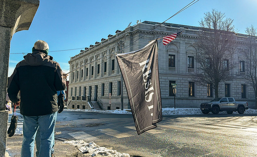 A protester holds a "Resist" flag in front of federal court in Portland, Maine, as Immigration and Customs Enforcement conduct operations in the state, Jan. 22, 2026. (AP/Rodrique Ngowi)