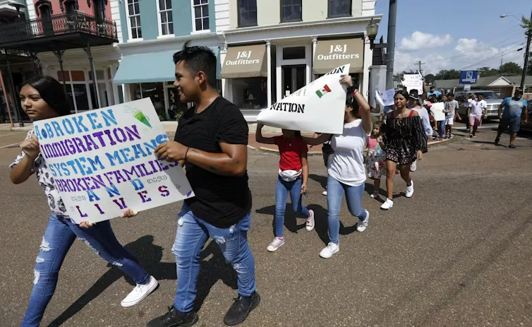 Young Latinos hold signs in support of workers picked up during a 2019 immigration raid at a food processing plant in Canton, Miss., following a Spanish Mass at Sacred Heart Catholic Church. (AP/Rogelio V. Solis)