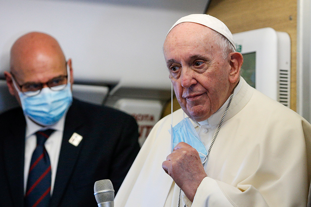 Pope Francis takes off his mask as he greets journalists aboard his flight from Rome to Baghdad March 5, 2021. (CNS/Paul Haring)