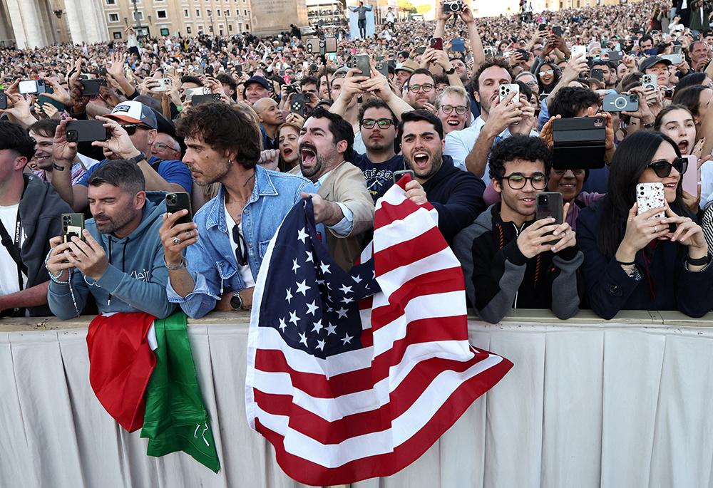 Men wave a U.S. flag as Cardinal Robert Francis Prevost, who had chosen the papal name Leo XIV, appears on the central balcony of St. Peter's Basilica at the Vatican May 8, 2025, following his election during the conclave. (OSV News/Reuters/Eloisa Lopez)