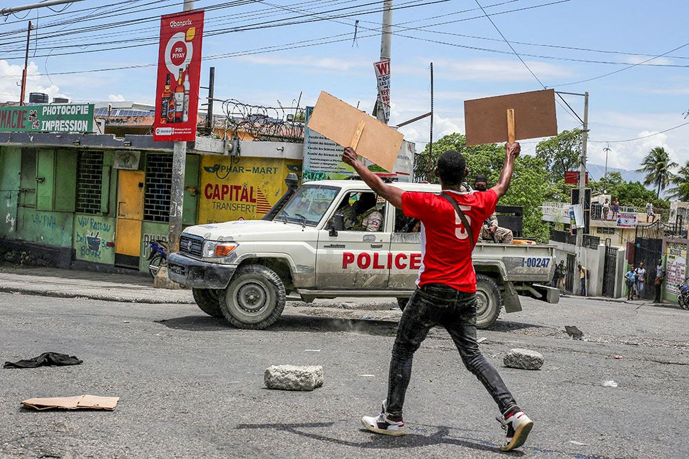 A man holds up placards as he yells toward a patrol car during a protest against gang-related violence in Port-au-Prince, Haiti, May 15, 2025. (OSV News/Reuters/Jean Feguens Regala)
