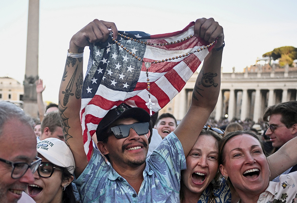 A man holding a rosary and U.S. flag reacts as Cardinal Robert Francis Prevost, who has chosen the papal name Leo XIV, appears on the central balcony of St. Peter's Basilica at the Vatican May 8, 2025, following his election during the conclave. (OSV News/Reuters/Dylan Martinez)