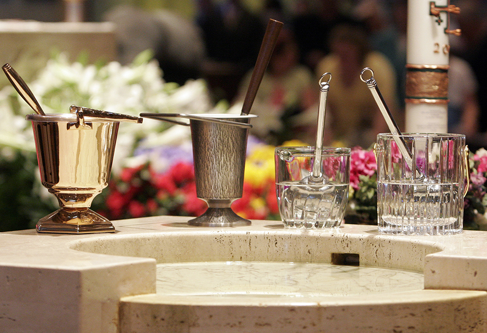 Aspersoriums with aspergillums used for sprinkling holy water are seen near a baptismal font during Easter Mass at a church in New York, in this file photo. (OSV News/Gregory A. Shemitz)