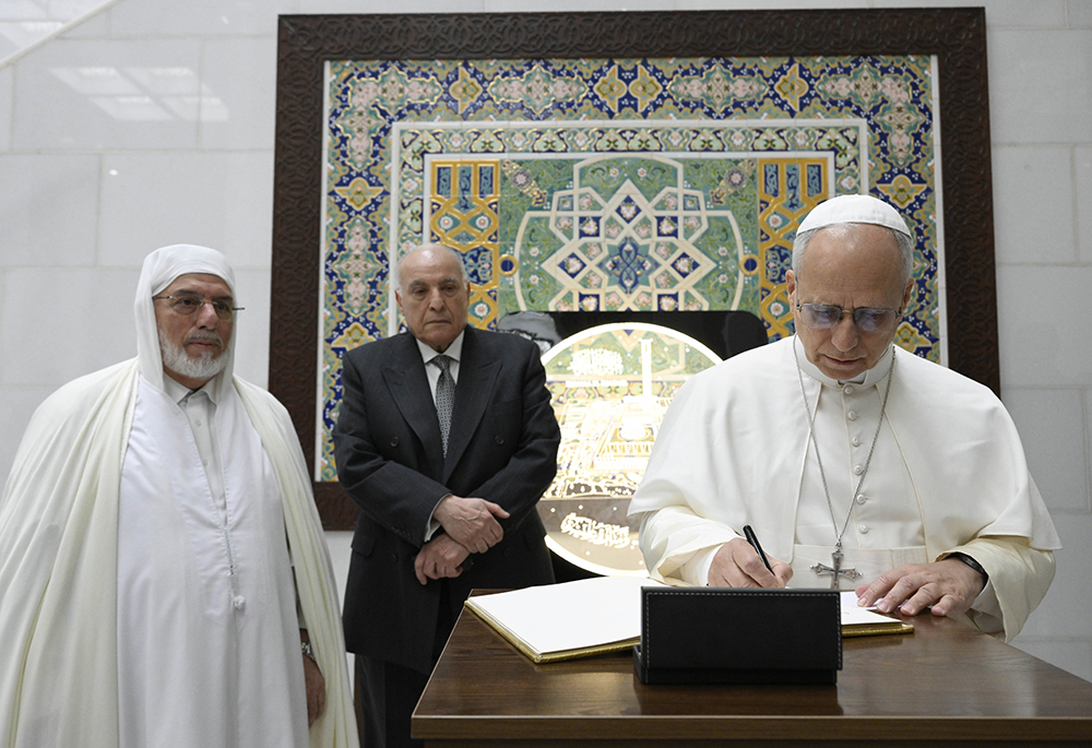Pope Leo XIV signs a book, alongside Mohamed Mamoun Al Qasimi, rector of the Great Mosque of Algiers, as he visits the mosque in Algiers, Algeria, April 13, 2026. The pontiff visited the mosque, one of the largest in the world, in a gesture aimed at reinforcing Christian-Muslim dialogue. (OSV News/Vatican Media/Simone Risoluti)