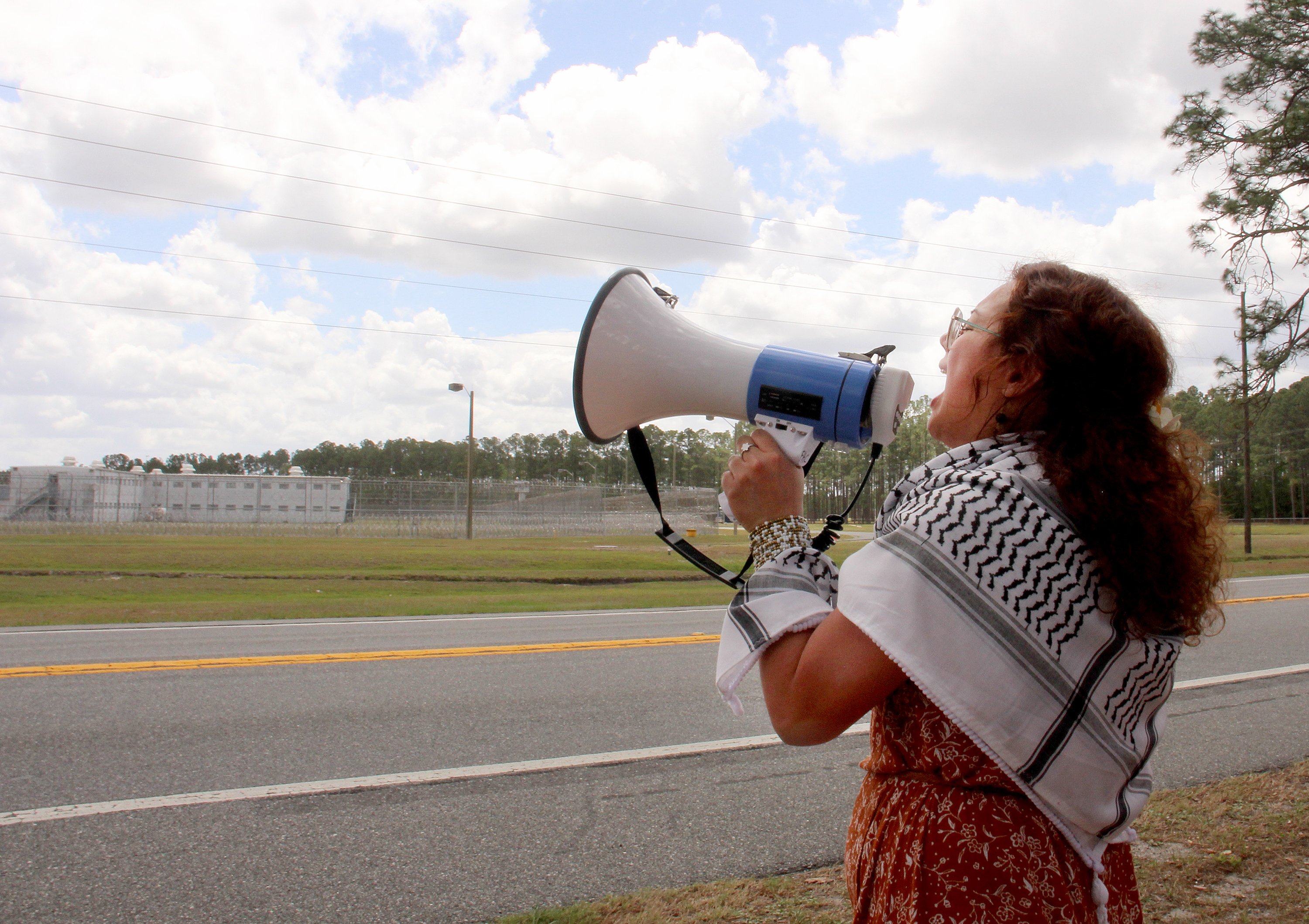 After hearing detainees in the Deportation Depot facility start to whistle to let advocates know they could hear their prayers, Amarilys Sanchez Cardenas, a college student in Austin, Texas, from Jacksonville, Fla., sings "Pregón Pascual," an Easter prayer, April 3, 2026. Advocates walked across the street from Deportation Depot, the former Baker Correctional Institution used to house immigrant detainees. 