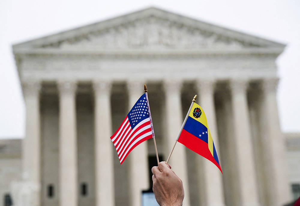 A person holds U.S. and Venezuelan flags as immigrants' rights activists and demonstrators attend a rally outside the U.S. Supreme Court in Washington April 29, 2026, as justices heard arguments on whether the administration of U.S. President Donald Trump can end the temporary protected status of Syrian and Haitian nationals. (OSV News/Reuters/Nathan Howard)