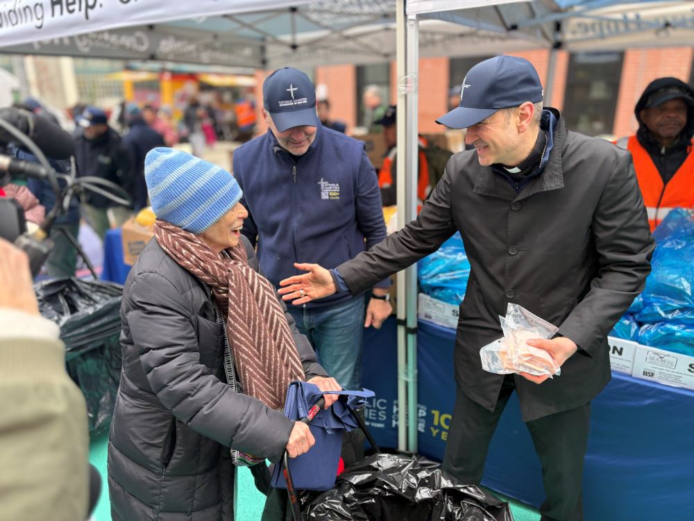Archbishop Ronald Hicks of New York, right, and CEO of Catholic Charities New York Antonio Fernandez help volunteers distribute food to residents of Washington Heights in Northern Manhattan, on Holy Thursday, April 2. (NCR photo/Camillo Barone)