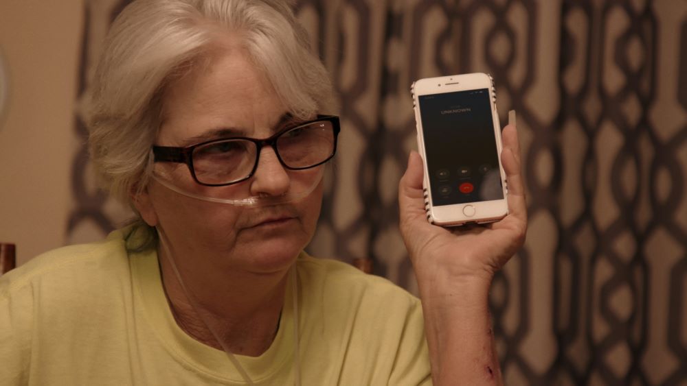 An image from the documentary "The Alabama Solution" shows a woman holding a cellphone.