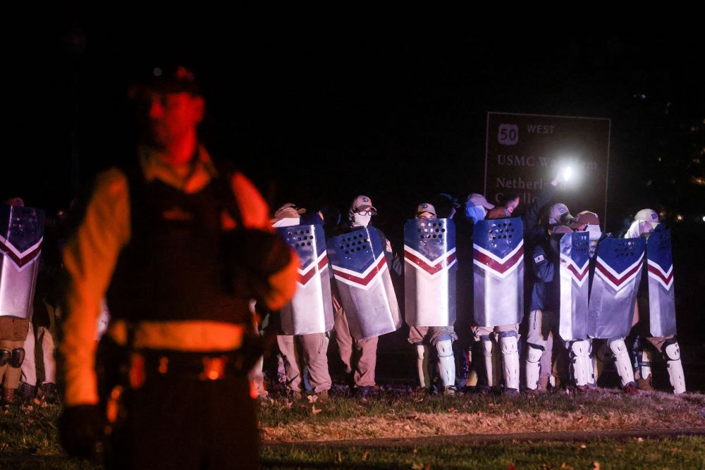 Members of Patriot Front, a white supremacist group, stand with shields in Arlington, Va., as a law enforcement officer stands guard between them, media members and bystanders Dec. 4, 2021. Members of the group held a "reclaim America" rally near the Lincoln Memorial in Washington. (CNS/Reuters/Leah Millis)
