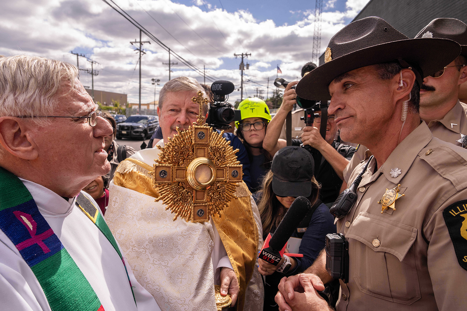 A member of the Illinois State Police, right, relays the message to clergy that U.S. Immigration and Customs Enforcement denied them access to detainees to provide Communion, outside an ICE facility in Broadview, Ill., Oct. 11, 2025. (RNS/AP/Adam Gray)