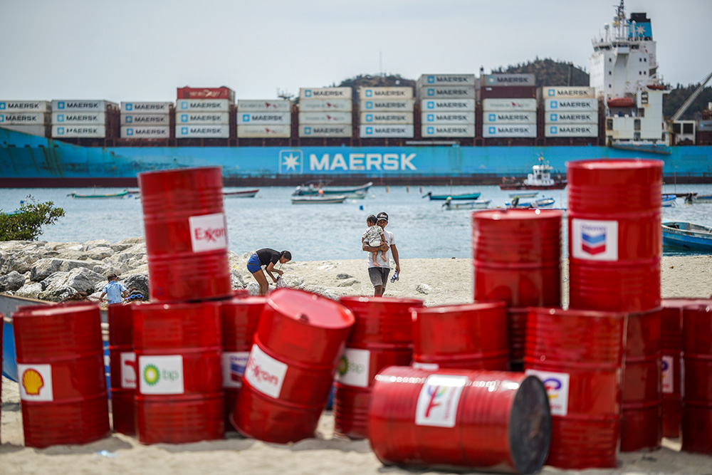 A family walks near a Make Polluters Pay demonstration along the Caribbean Sea April 27, 2026, in Santa Marta, Colombia. Protesters were demanding oil companies pay for the energy transition during a nearby conference aimed at transitioning away from fossil fuels. (AP/Ivan Valencia)