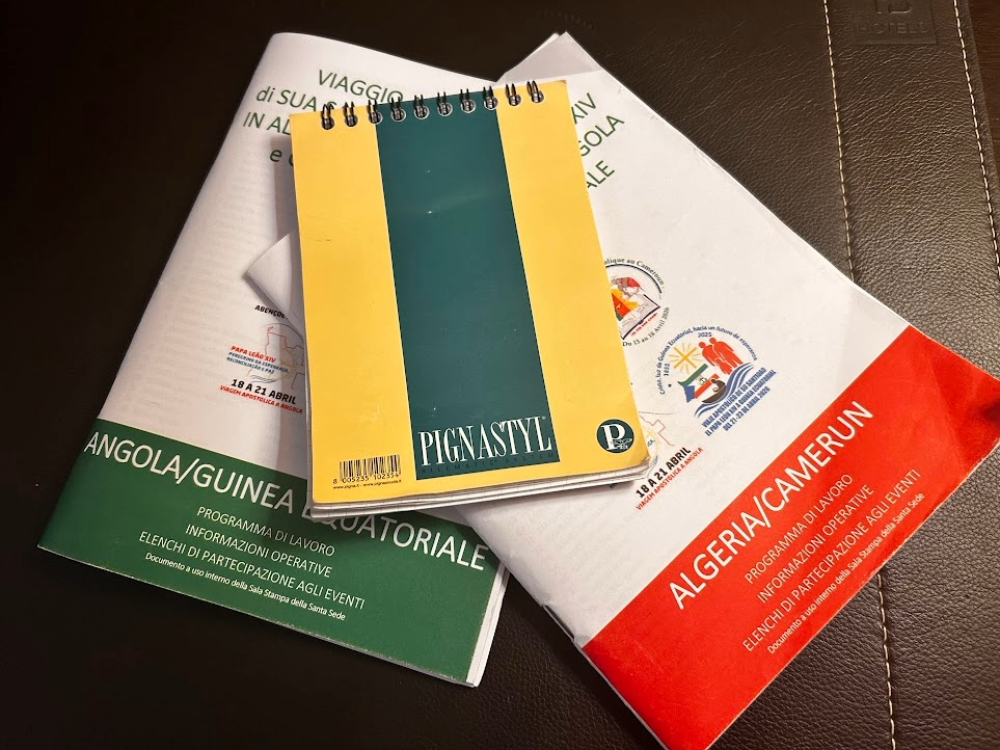 The notebook used by NCR Vatican correspondent Justin McLellan during his trip through Africa with the pope laid on top of two programs.