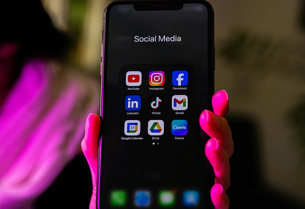A smartphone displays social media app icons in this pink-hued photo illustration. (Unsplash/dlxmedia.hu)