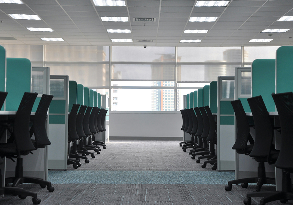 An office setting features empty rolling chairs at cubicles in this photo illustration. (Unsplash/Kate Sade)