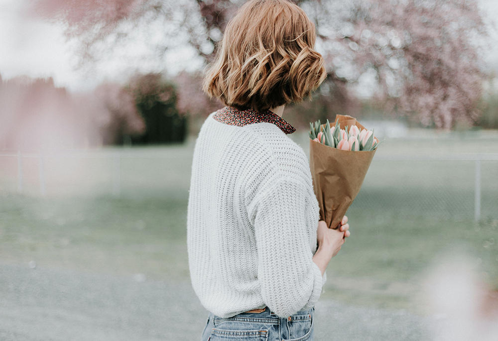 A woman holds a bouquet of flowers in this outdoor setting. (Unsplash/Priscilla Du Preez)