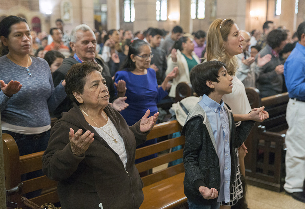 Worshippers recite the Lord's Prayer during an Oct. 14, 2018, Mass at the Shrine of the Sacred Heart in Washington, celebrating the canonization of St. Oscar Romero. Around 800 people, mostly immigrants, attended the Mass and a parish celebration afterward. (CNS/Catholic Standard/Jaclyn Lippelmann)
