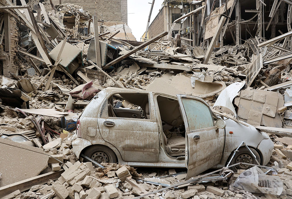 A destroyed vehicle is seen amid rubble at the site of a strike on a residential building in Tehran, Iran, March 16, 2026, amid the U.S.-Israeli war with Iran. (OSV News/WANA via Reuters/Majid Asgaripour)
