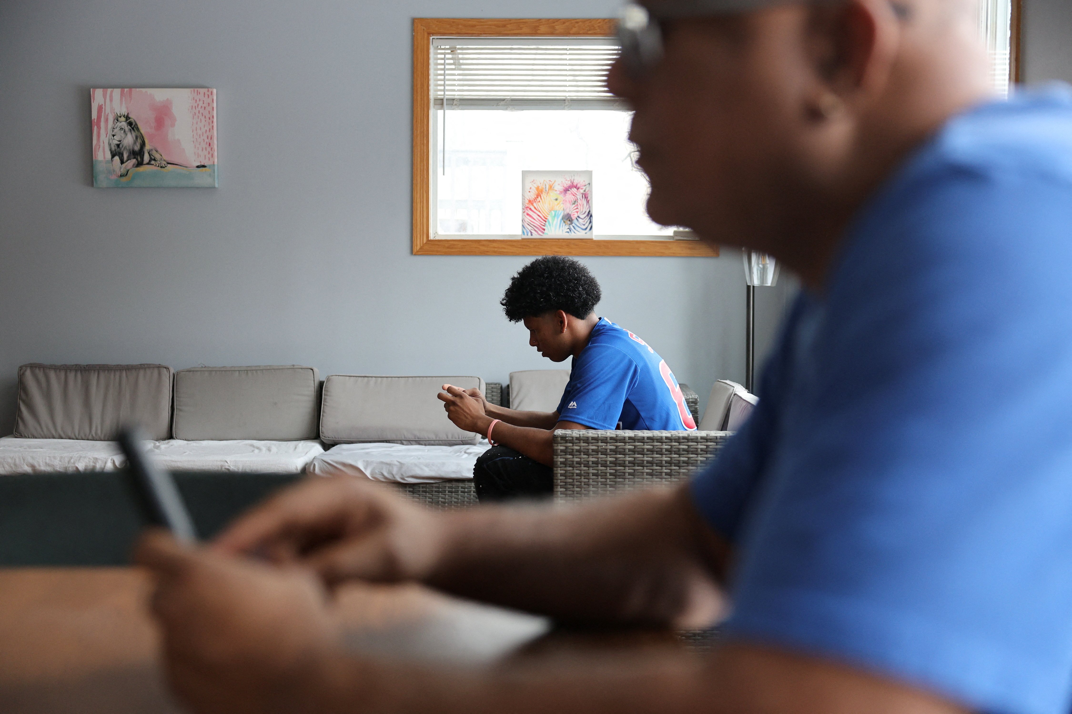 Joseph Thomas, 18, who migrated to the U.S. from Venezuela with his family in 2023, looks at his phone in his house in St. Paul, Minn., Feb. 7, 2026. The U.S. bishops and other Catholic groups have issued public comments expressing concern about still-pending proposed federal regulations that would further restrict asylum-seekers and other migrants and their families from work authorization and housing assistance.