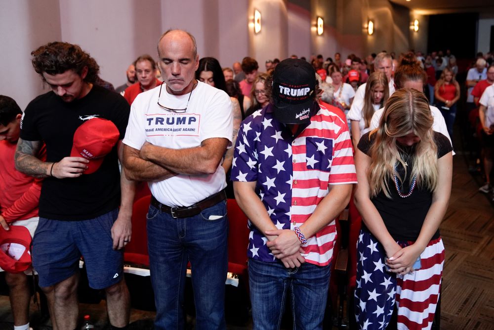 Audience members stand and pray before Republican presidential candidate former President Donald Trump arrives to deliver remarks on the tax code, and manufacturing at the Johnny Mercer Theatre Civic Center Sept. 24, 2024, in Savannah, Ga. (AP/Evan Vucci)