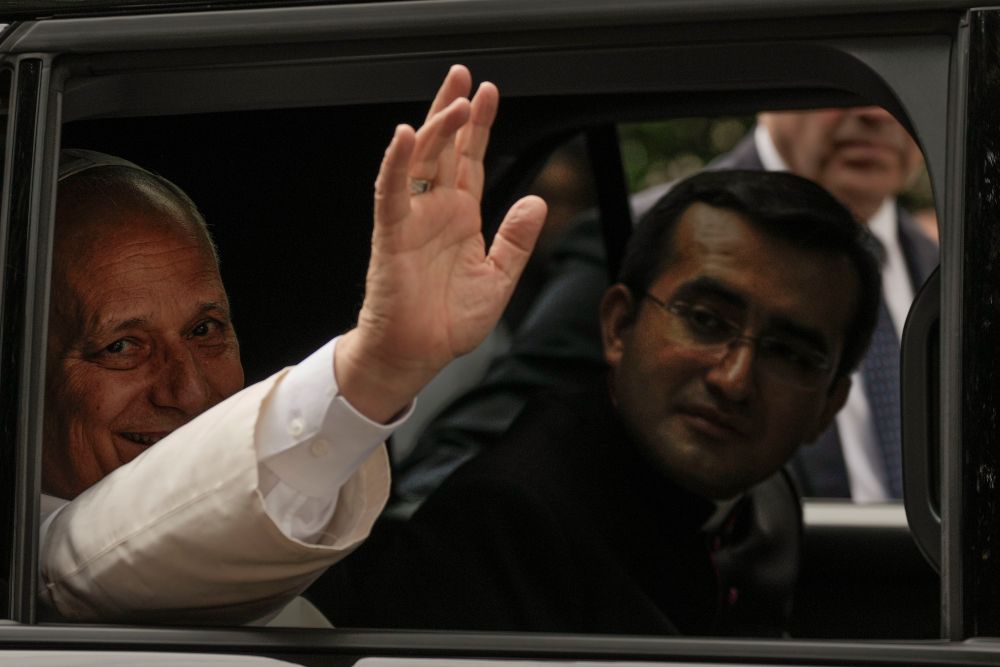 Pope Leo XIV waves from his car as he leaves with his personal secretary, Msgr. Edgard Iván Rimaycuna Inga, right, after visiting the Città Universitaria (University City) at Sapienza University of Rome May 14, 2026. (AP/Gregorio Borgia)