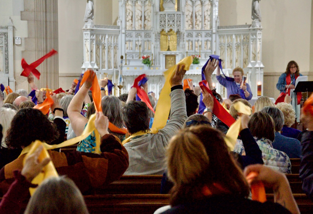 Attendees at the Women's Ordination Conference's 50th anniversary celebration wave multi-colored stoles Friday, May 22, 2026, in Detroit. (NCR photo/Dan Stockman)