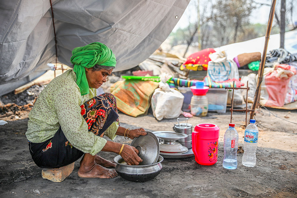 A Rohingya woman cooks in her makeshift tent March 24, 2021, after a fire broke out March 22 at a refugee camp in Cox's Bazar, Bangladesh. (CNS/Reuters/Mohammad Ponir Hossain)
