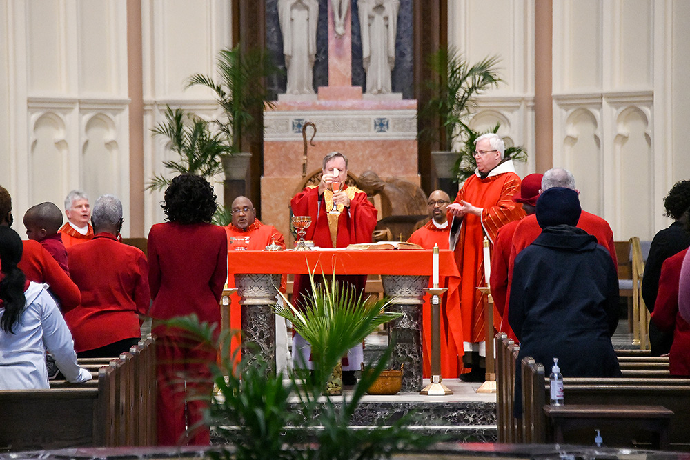 Bishop Robert McClory of Gary, Ind., raises the host and chalice during Palm Sunday Mass at the Cathedral of the Holy Angels in Gary April 10, 2022, as Franciscan Fr. Michael Surufka concelebrates. (CNS/Northwest Indiana Catholic/Anthony D. Alonzo)