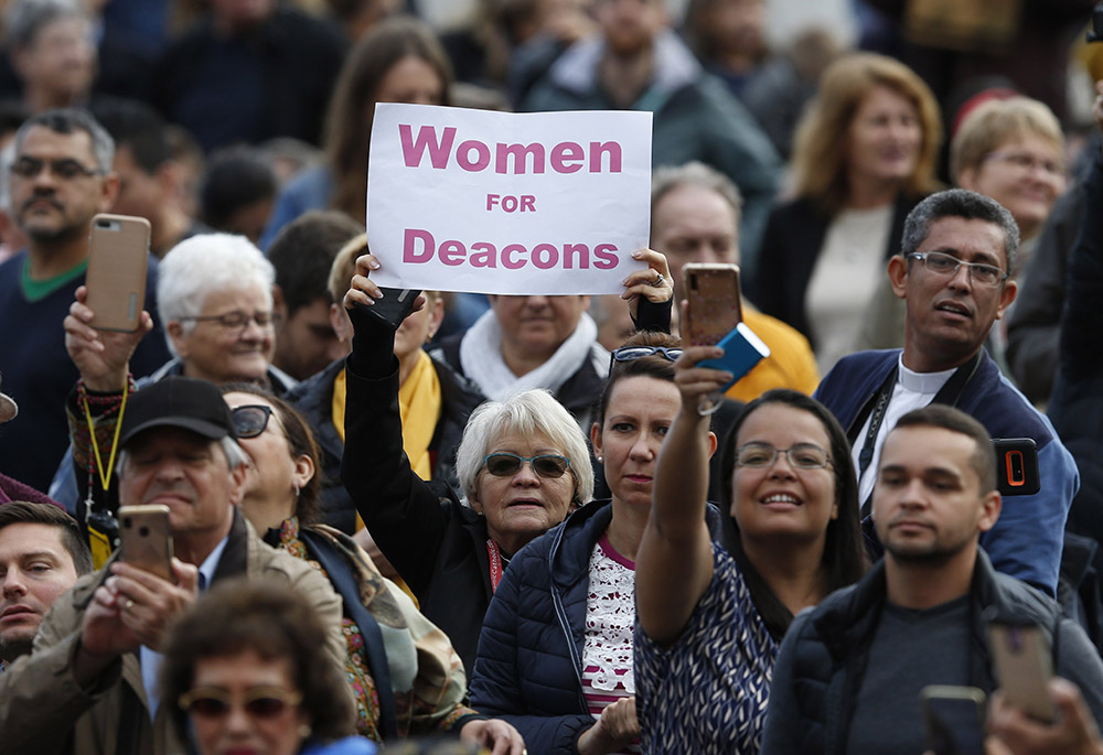 A woman holds a sign in support of women deacons as Pope Francis leads his general audience in St. Peter's Square at the Vatican Nov. 6, 2019. (CNS/Paul Haring)