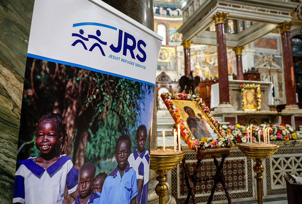 A sign from the Jesuit Refugee Service is displayed during an ecumenical prayer vigil in Rome's Basilica of Santa Maria in Trastevere Feb. 6, 2024, as part of a week of raising awareness about human trafficking. (CNS photo/Lola Gomez)
