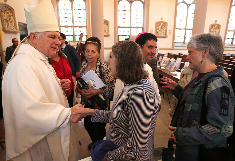 Miami Archbishop Thomas G. Wenski and Bishop Oscar Cantu, then head of the Diocese of Las Cruces, New Mexico, are pictured in a 2014 file photo greeting people after celebrating a "Mission for Migrants" Mass at St. Peter's Catholic Church on Capitol Hill in Washington. (OSV News/Bob Roller)