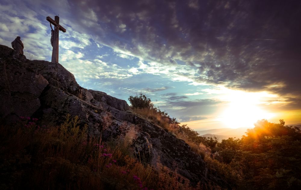 crucifix on a hill under cloudy sky
