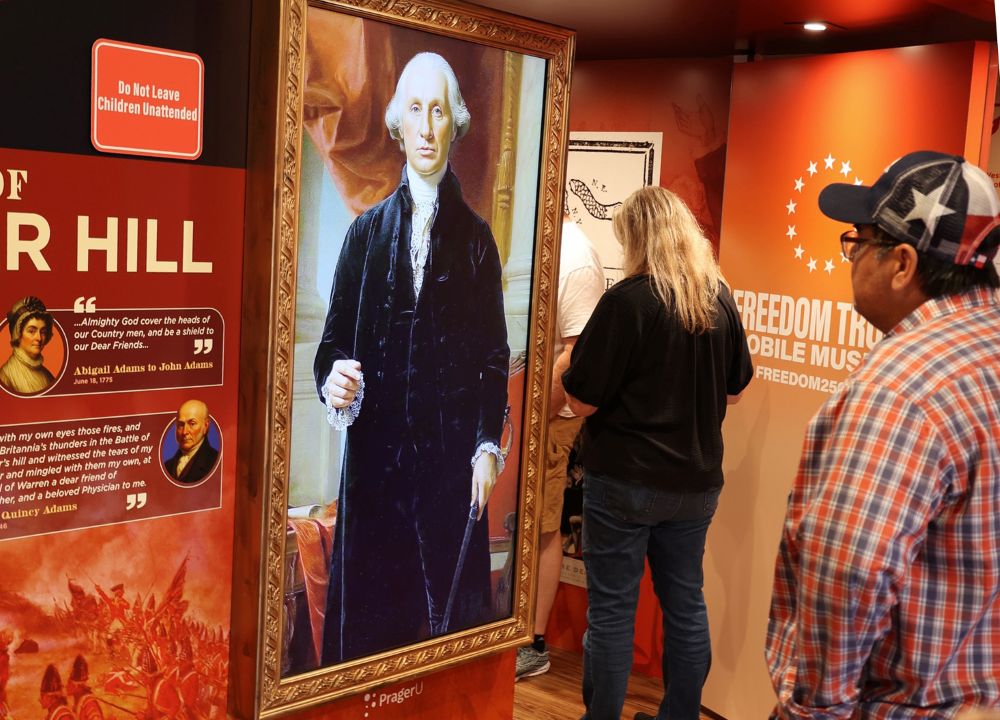 A visitor stands in front of an AI-animated image of George Washington inside the "Freedom Truck" parked at the La Crosse convention center for the "Zeale for America 250 Rally." (Martyn Smith)