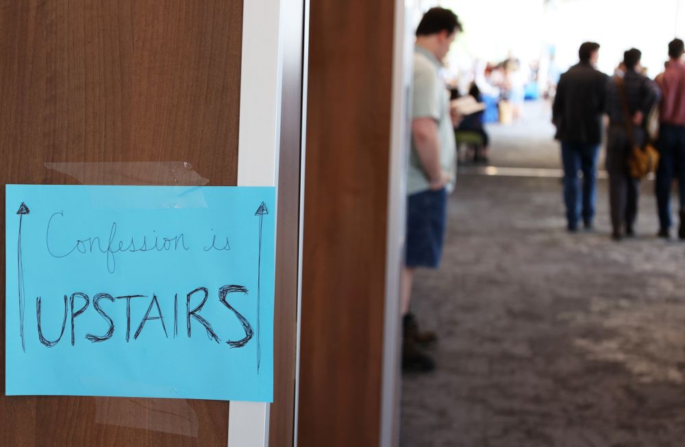 A sign in the convention center at the La Crosse convention center in Wisconsin points attendees at the  "Zeale for America 250 Rally" to a space upstairs where the sacrament of confession is available. (Martyn Smith)