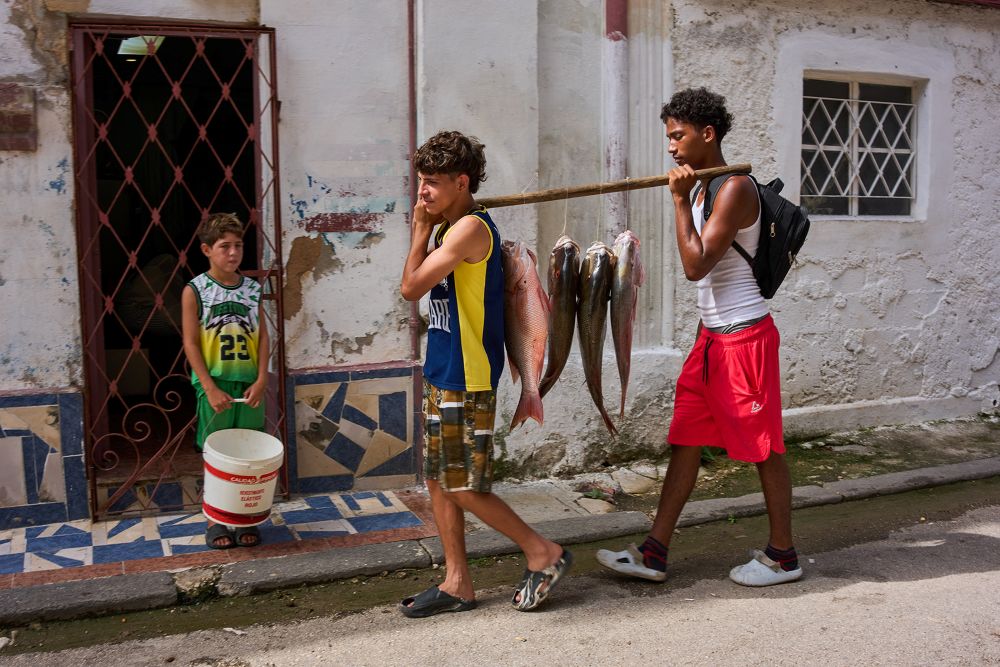Youths carry freshly caught fish from the sea in Havana, Cuba, Monday, June 1, 2026. (RNS/AP/Ramon Espinosa)