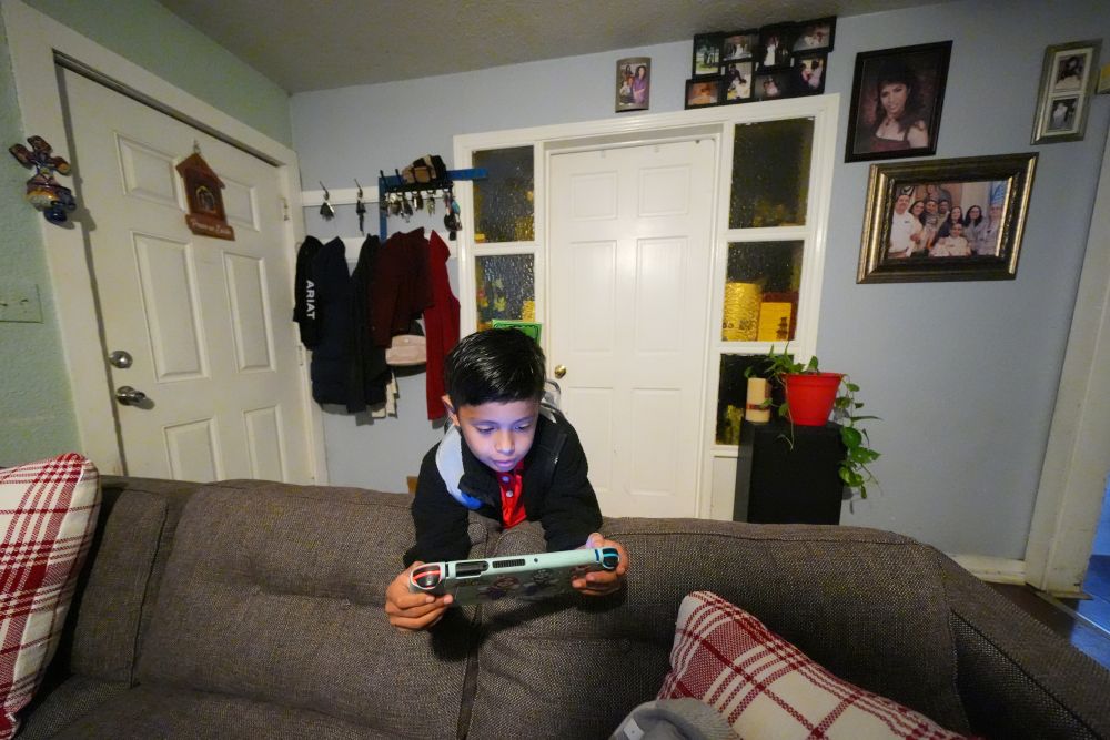Ian Contreras plays on a gaming device while waiting for his mother to take him to school April 9, 2026, in Fort Worth, Texas. (AP/Julio Cortez)