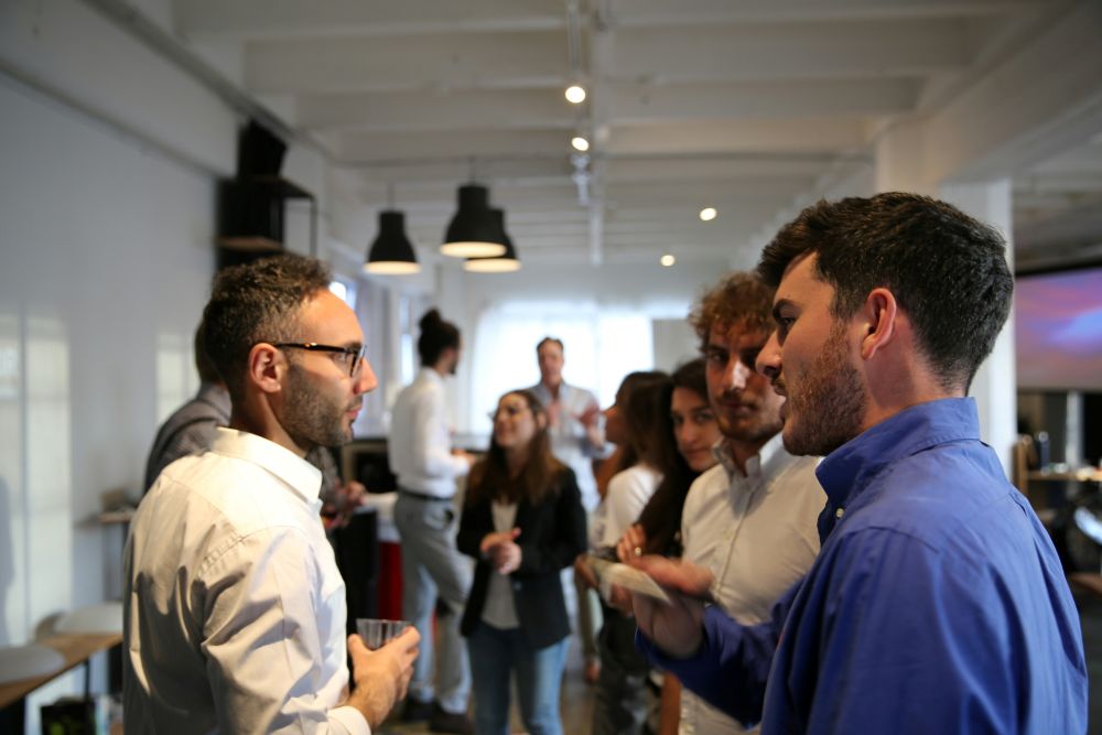 People hold glasses and talk to each other.