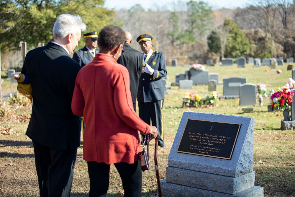 People pause to view a memorial marker to the unknown enslaved people buried at St. Peter Claver Parish's cemetery in St. Inigoes, Md., after Cardinal Wilton Gregory of Washington blessed the memorial Nov. 26, 2022. At least 24 parishes in the archdiocese have requested that memorial to honor formerly enslaved people buried in their cemeteries. (CNS/Catholic Standard/Ashley Barnas)