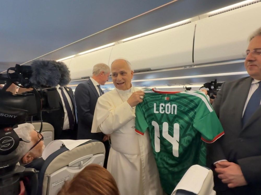 Pope Leo XIV holds a personalized Mexican soccer jersey given to him by Vatican journalist Valentina Alazraki, from Mexico, June 6, on the flight from Rome to Madrid at the start of his visit to Spain. Leo said he hoped the World Cup, which starts June 11, would be a source of unity. (Vatican press pool)
