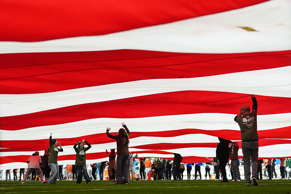 People support a large American flag on the field before the Fiesta Bowl NCAA college football playoff semifinal game between Miami and Mississippi Jan. 8, 2026, in Glendale, Ariz. (AP/Ross D. Franklin)