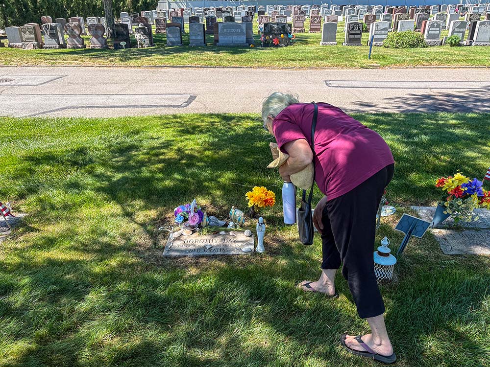 Martha Hennessy, Dorothy Day's granddaughter, bends over her grandmother's grave at Resurrection Cemetery in Staten Island, New York, June 8, 2026. (NCR photo/Camillo Barone)
