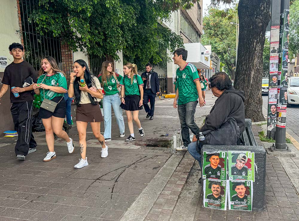 Soccer fans walk by a bench with photos of missing men July 4, 2026 in Guadalajara, Mexico. Families photoshopped the uniform of the Mexican soccer team on their loved ones to call attention to the missing. (GSR photo/Rhina Guidos)