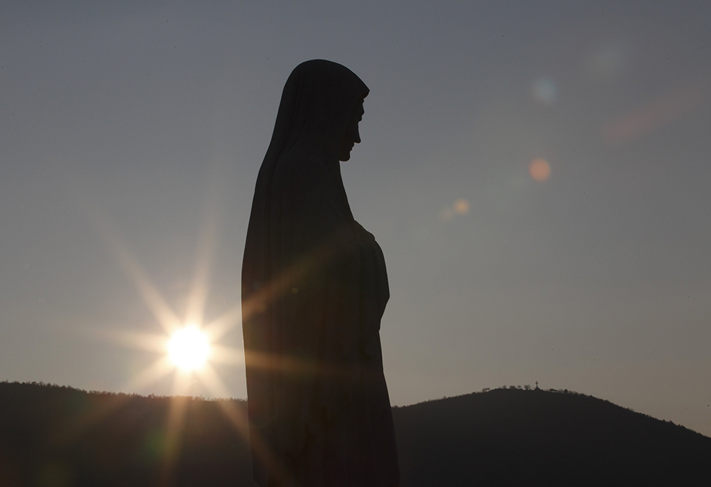 The sun sets behind a statue of Mary on Apparition Hill in Medjugorje, Bosnia-Herzegovina, in this Feb. 26, 2011, file photo. (CNS/Paul Haring)