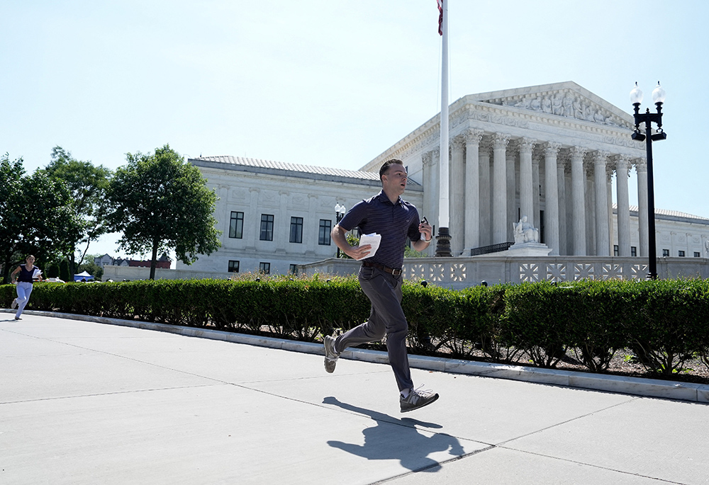 An intern runs outside the U.S. Supreme Court in Washington June 30, 2026, to deliver the court's ruling on birthright citizenship to the media. (OSV News/Reuters/Cheney Orr)