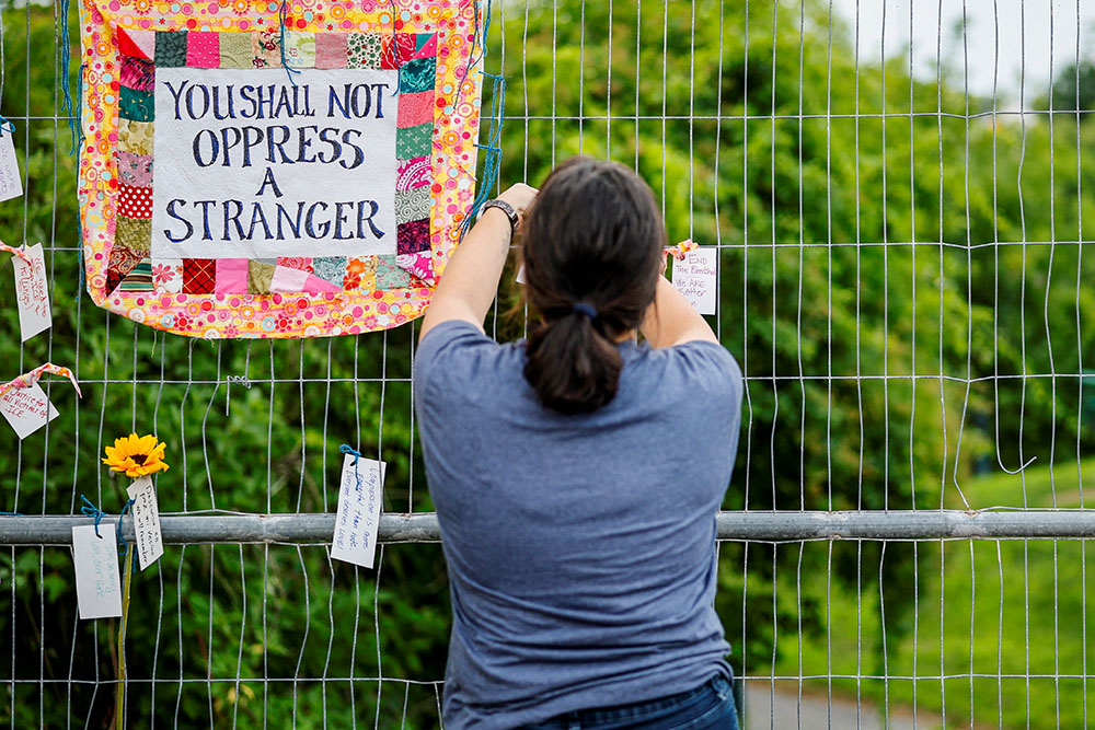 A woman places a message on a fence during a candlelight memorial service at Mechanics Park in Biddeford, Maine, July 13, 2026, after a U.S. Immigration and Customs Enforcement agent fatally shot a motorist. (OSV News/Reuters/CJ Gunther)