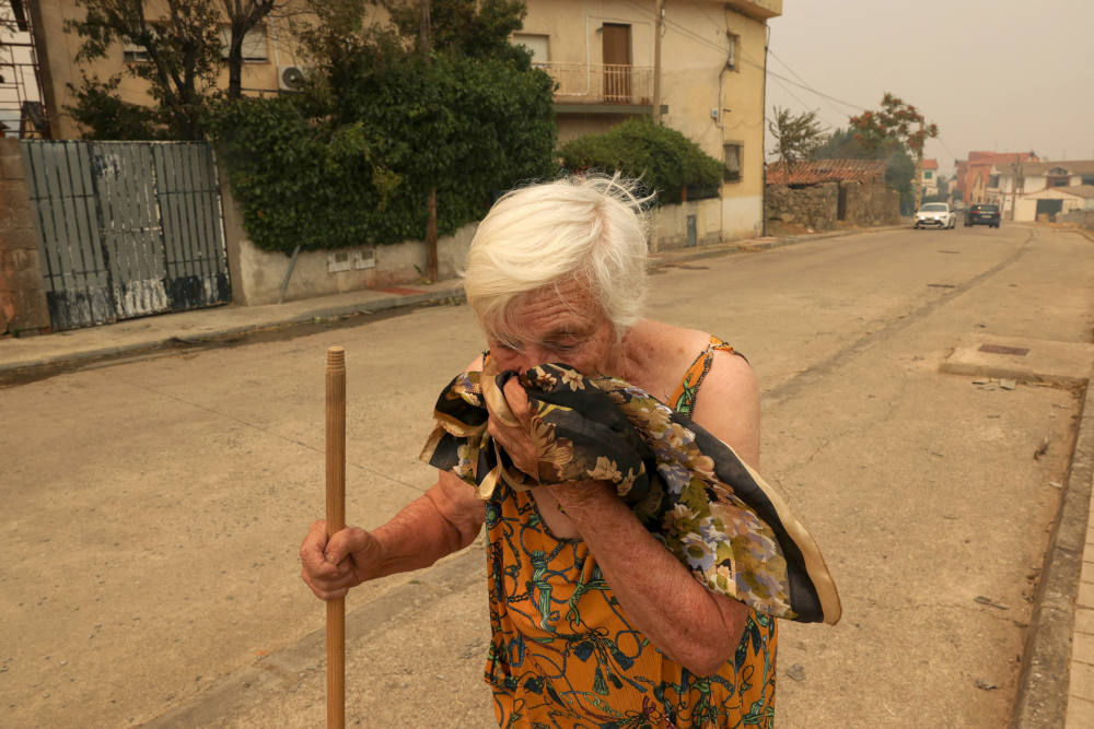 An elderly woman covers her face to protect herself from smoke in the Spanish village of El Tiemblo July 24, 2026, during a wildfire affecting Castilla y Leon province. (OSV News photo/Violeta Santos Moura, Reuters)