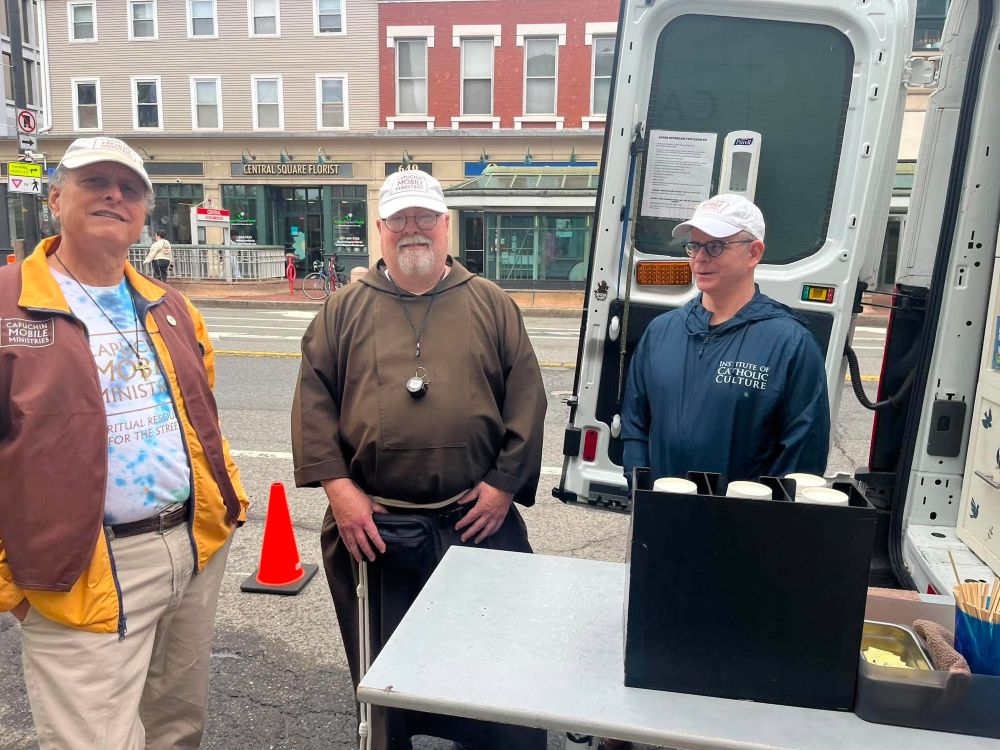 Lay chaplain Gary Riccio (left), Capuchin Franciscan Br. Paul Fesefeldt and a volunteer stand by the Capuchin Mobile Ministries van in Cambridge, Massachusetts, in mid-June. "It's like a mobile coffee hour," said Fesefeldt, founder and director of the ministry. (Greta Gaffin)