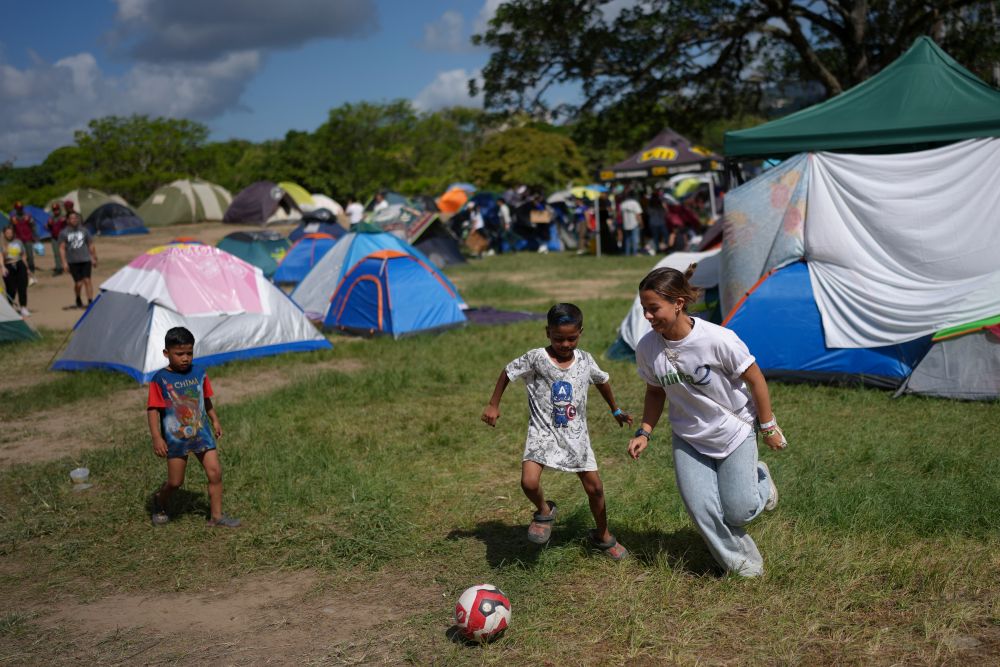 A volunteer plays soccer with children at Francisco de Miranda Park in Caracas, Venezuela, where people whose homes were damaged in the earthquakes are camping, Wednesday, July 1, 2026. (AP/Matias Delacroix)