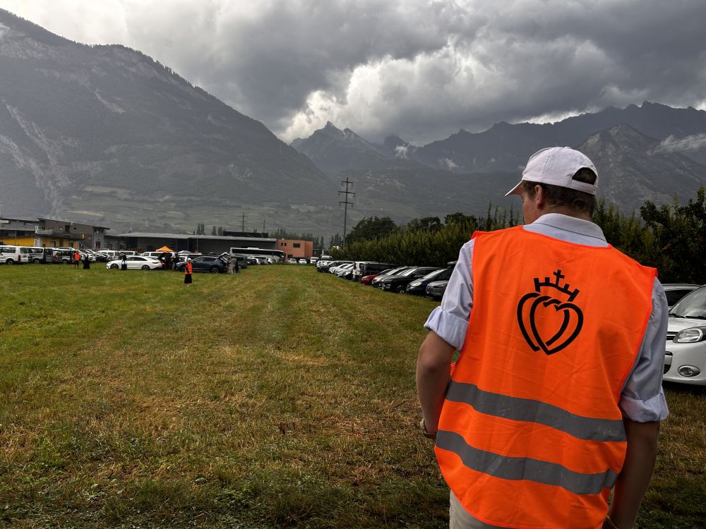 A volunteer directs parking in Écône, Switzerland, before a Mass for illicit bishop consecrations at the international seminary for the Society of St. Pius X July 1, 2026. (NCR photo/Justin McLellan)
